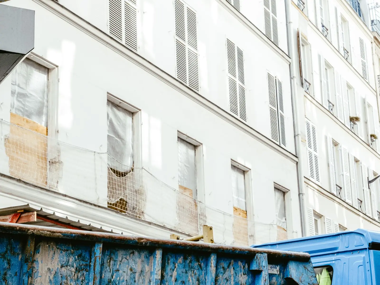 Benne à gravats devant la façade d'un immeuble ancien en travaux