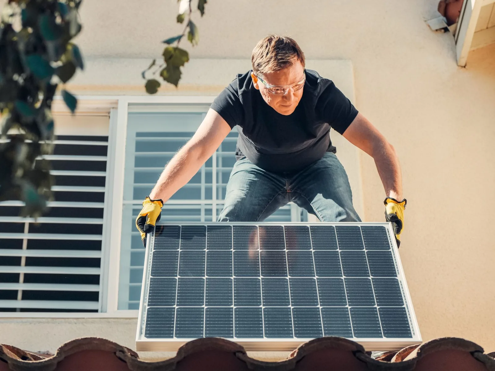 Technicien posant un panneau solaire sur le toit en tuiles d'une maison
