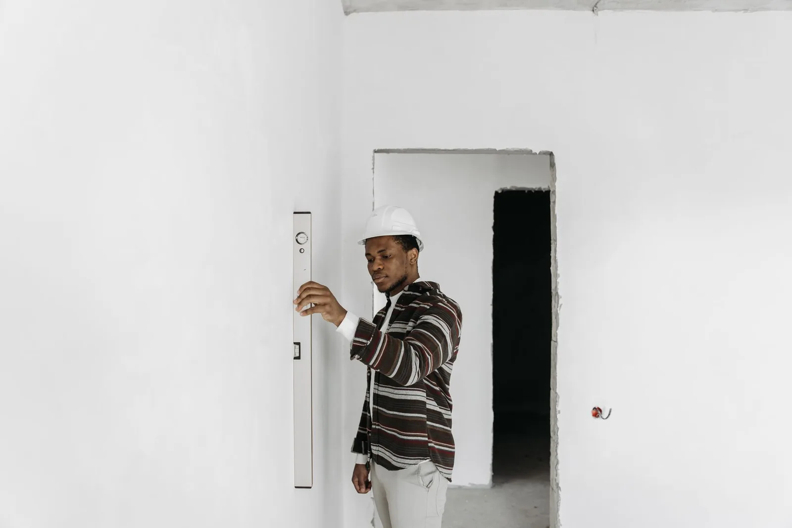 Homme casqué vérifiant un mur au niveau à bulle en chantier