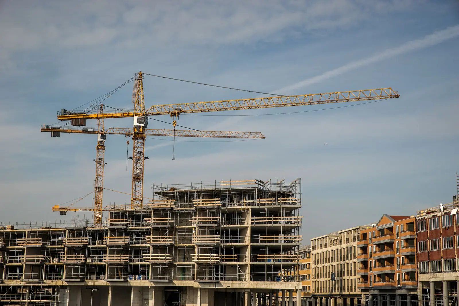 Deux grues à tour au-dessus d'immeubles en construction sous échafaudages