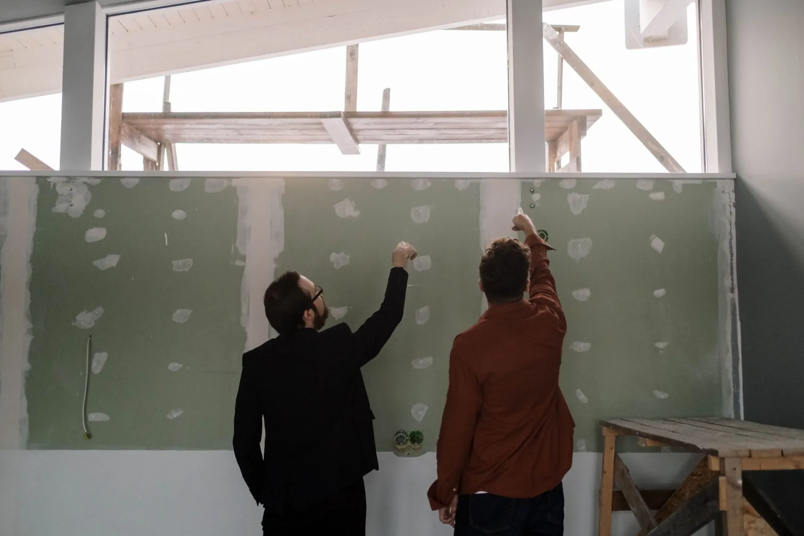 Deux hommes de dos observant une cloison en plaques de plâtre