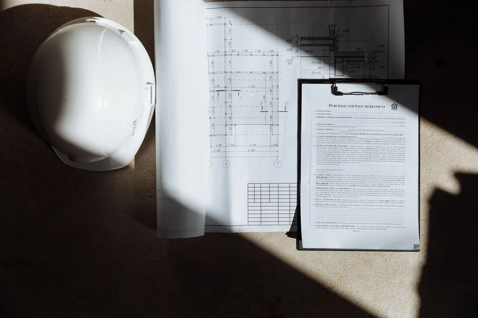Casque blanc, plan d'architecte et contrat posés sur une table