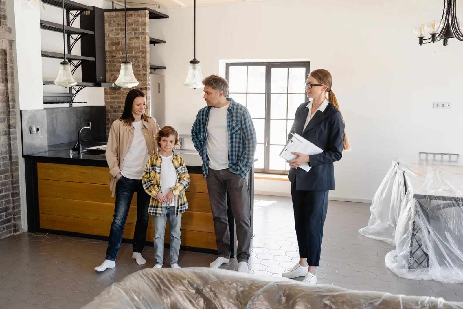 Une conseillère avec un porte-documents échange avec un couple et leur enfant dans une cuisine en travaux