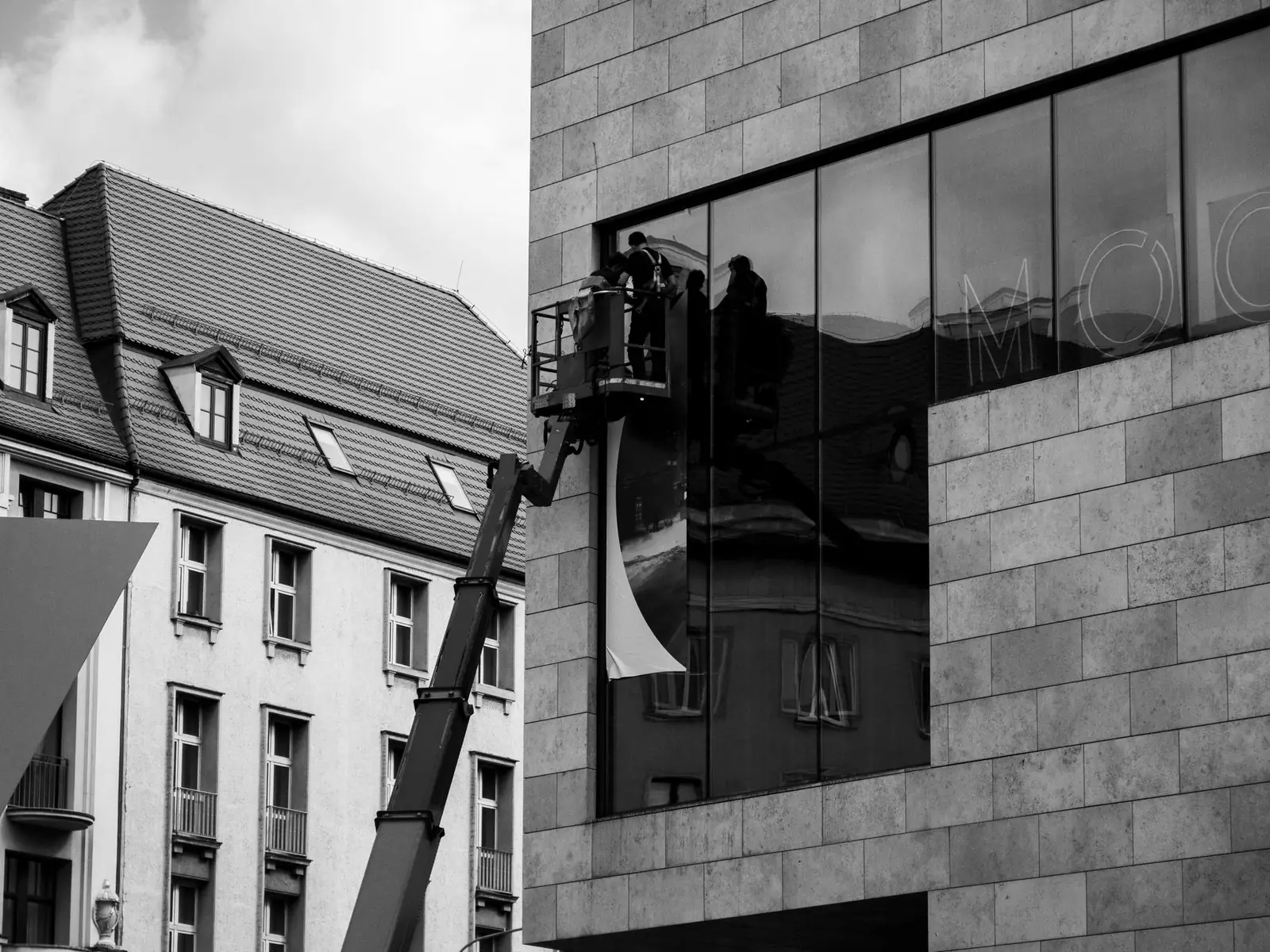 Ouvriers dans une nacelle élévatrice devant la façade vitrée d'un immeuble