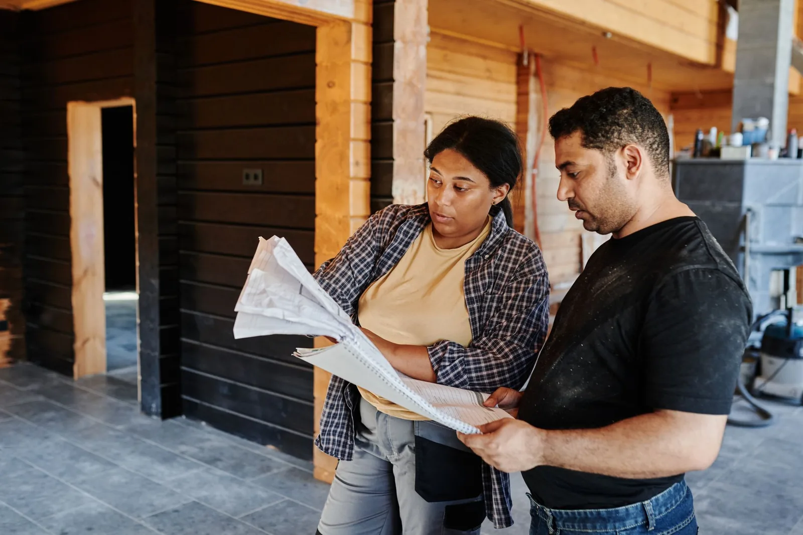 Deux artisans consultant des documents dans une maison en chantier