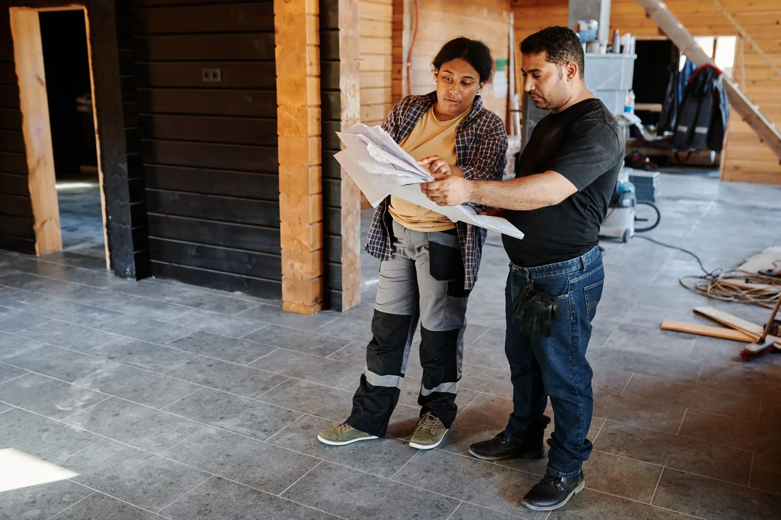 Deux artisans du bâtiment consultant des plans sur un chantier