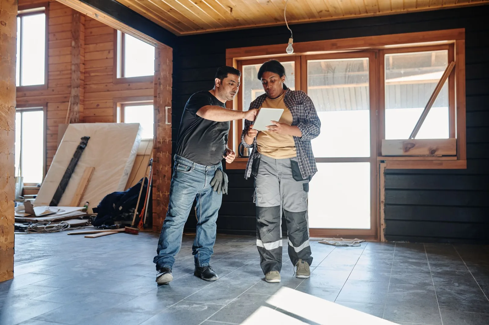 Deux artisans consultant une tablette dans une maison en rénovation