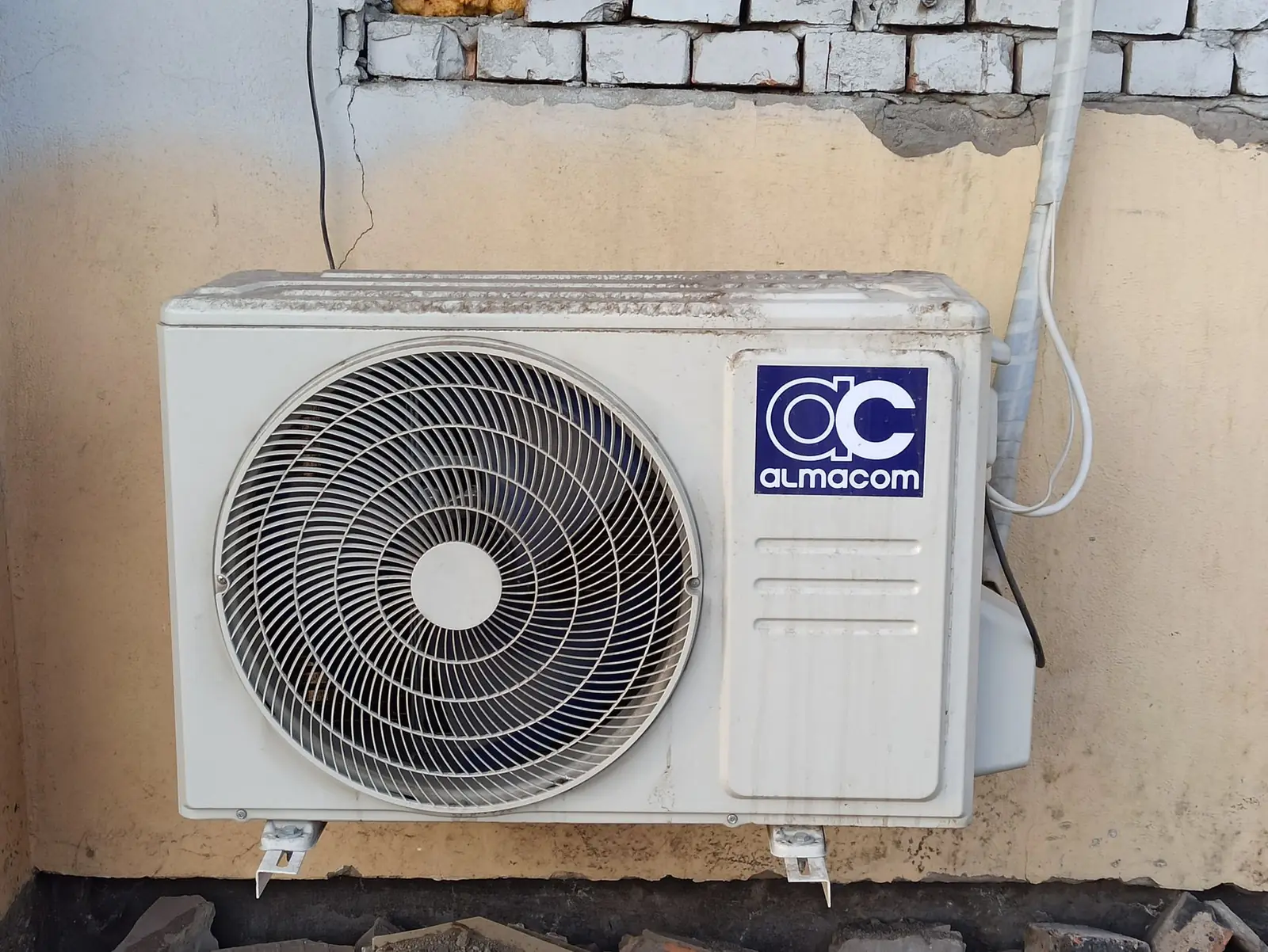 Unité extérieure de climatisation fixée sur un mur de façade fissuré
