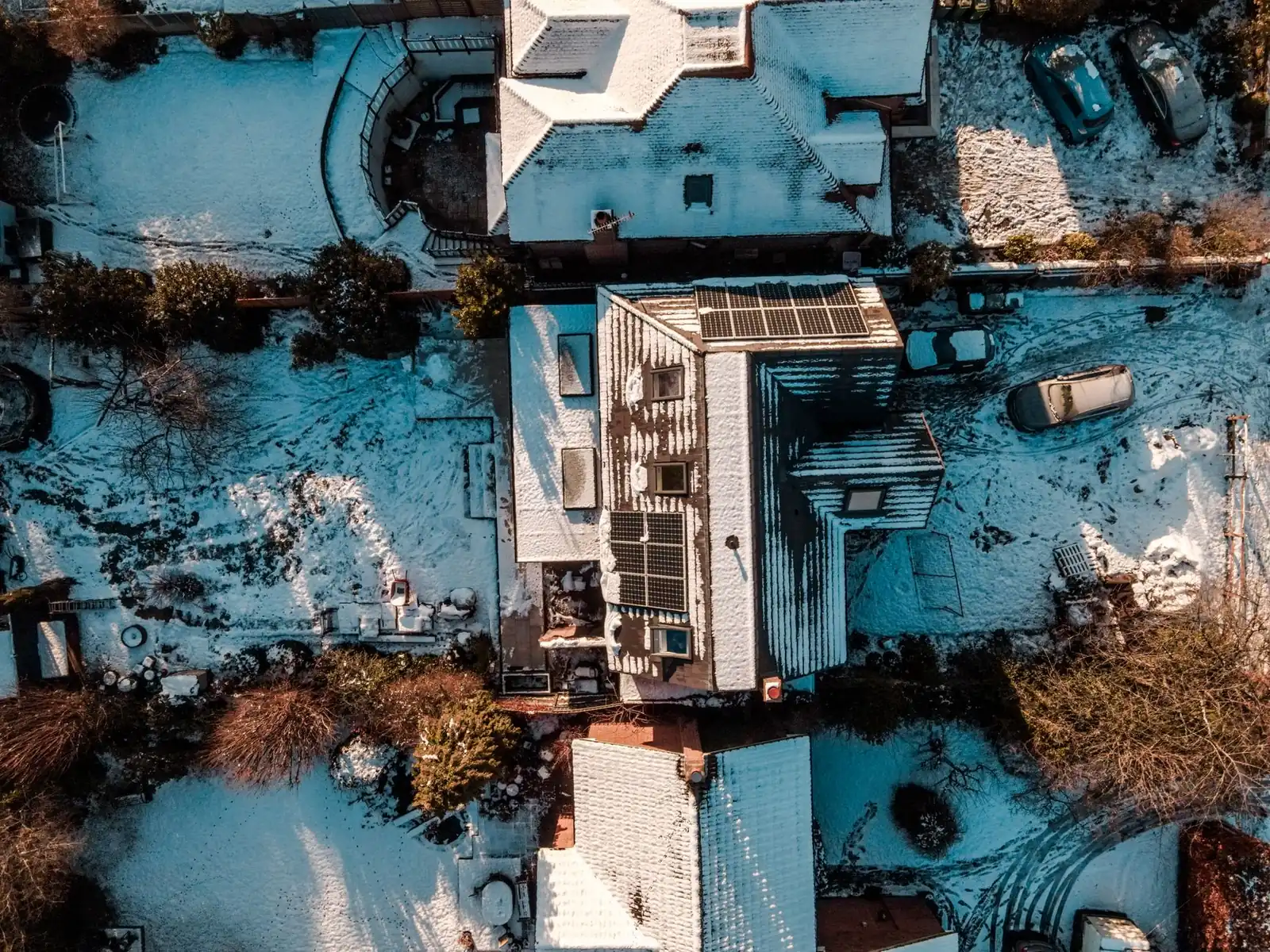 Vue aérienne d'une maison enneigée avec des panneaux solaires sur le toit