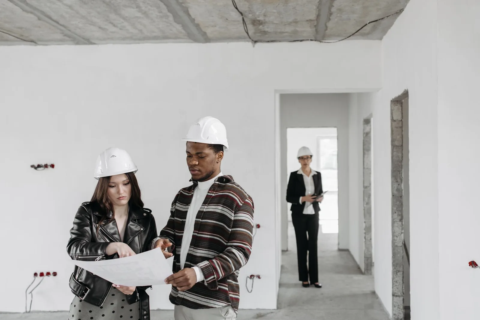Deux personnes casquées examinant un plan dans un logement en travaux