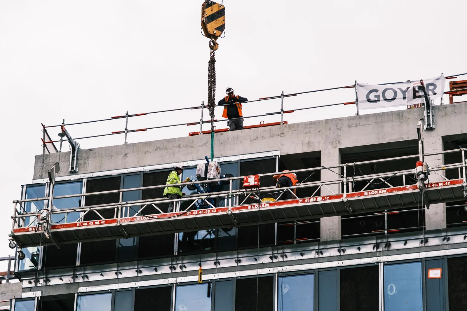 Ouvriers sur une nacelle suspendue travaillant sur la façade d'un immeuble
