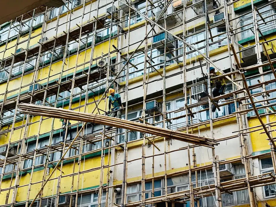 Ouvriers sur un échafaudage en bambou devant la façade d'un immeuble