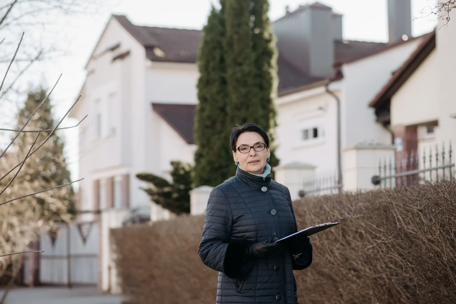 Conseillère en rénovation avec un porte-bloc devant des maisons individuelles