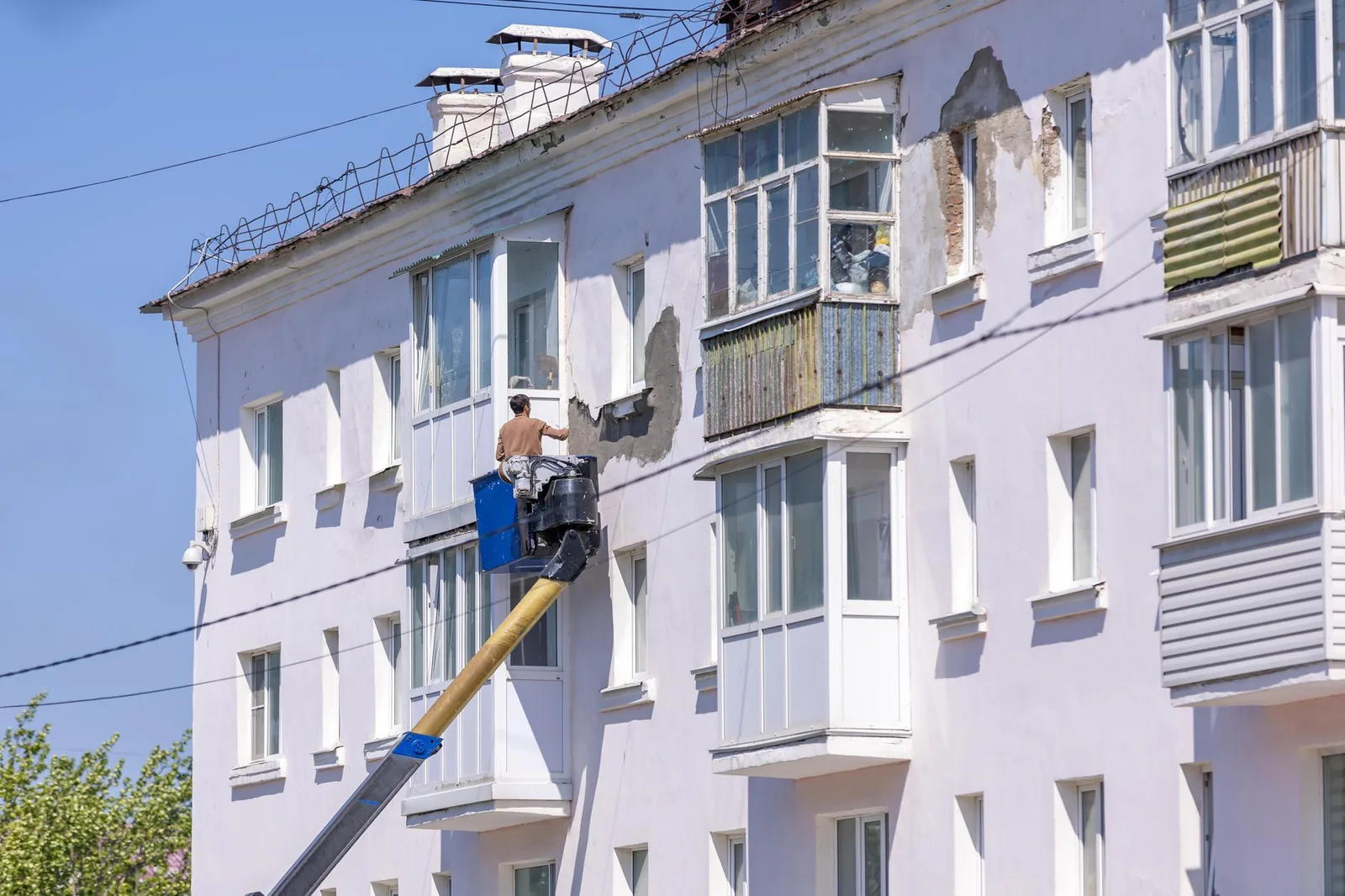 Ouvrier en nacelle élévatrice reprenant l'enduit de la façade d'un immeuble