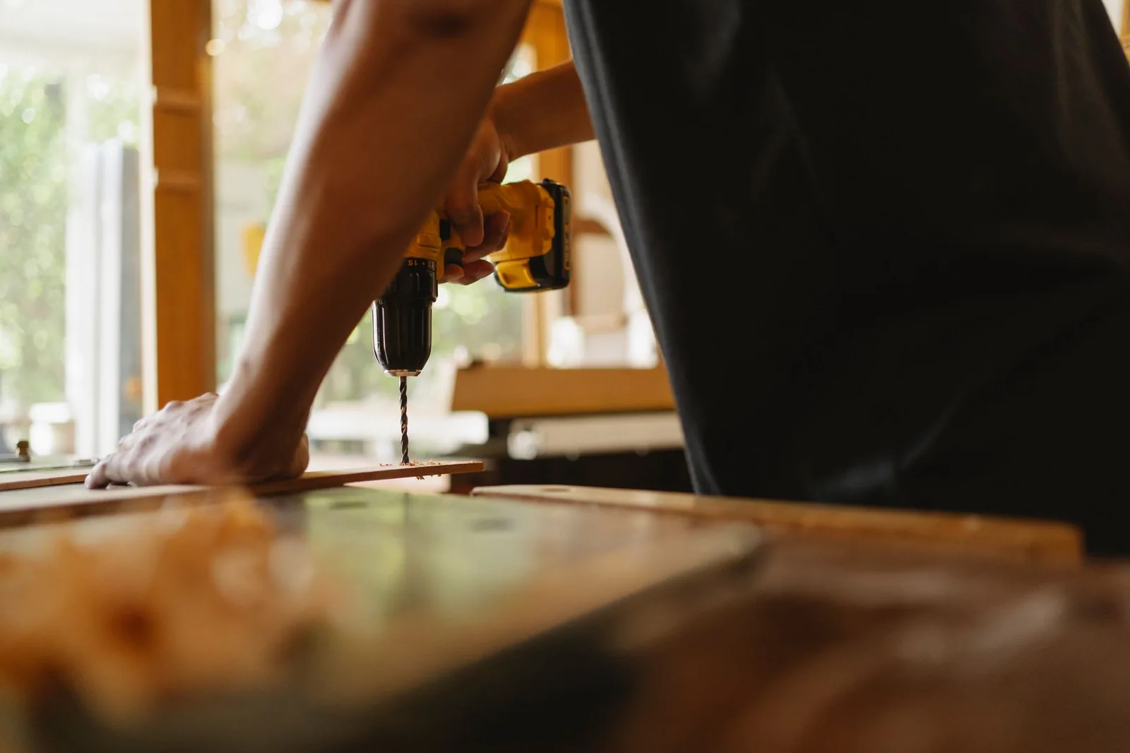 Artisan vissant une menuiserie en bois à la visseuse
