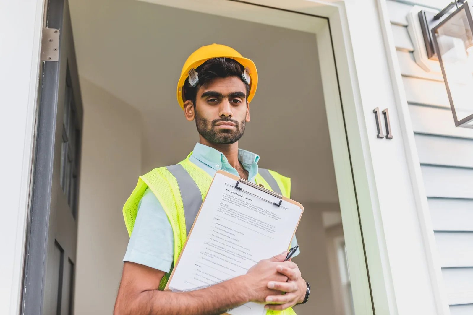 Artisan en casque et gilet de chantier consultant un dossier