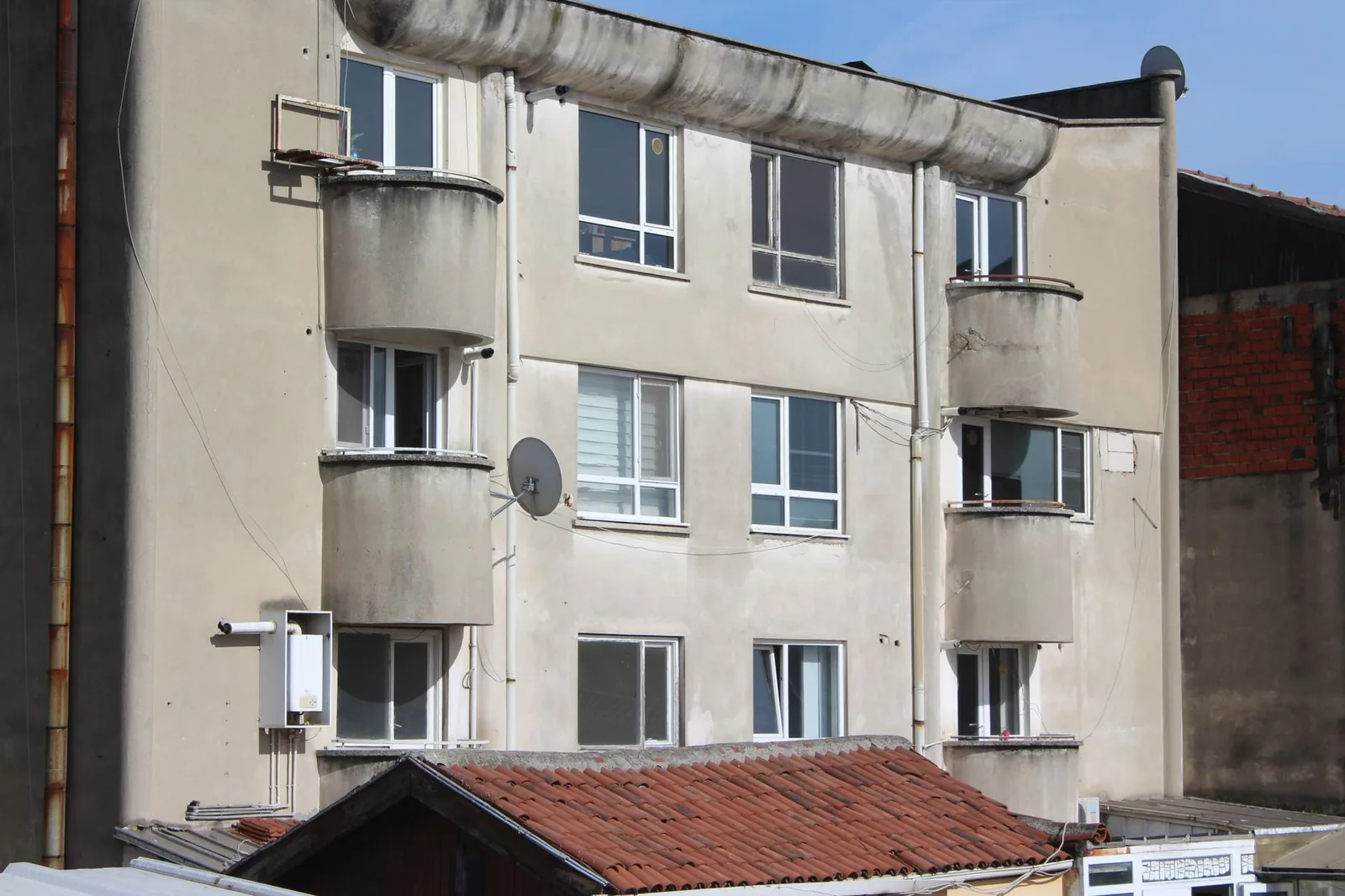Façade défraîchie d'un petit immeuble d'habitation avec balcons arrondis