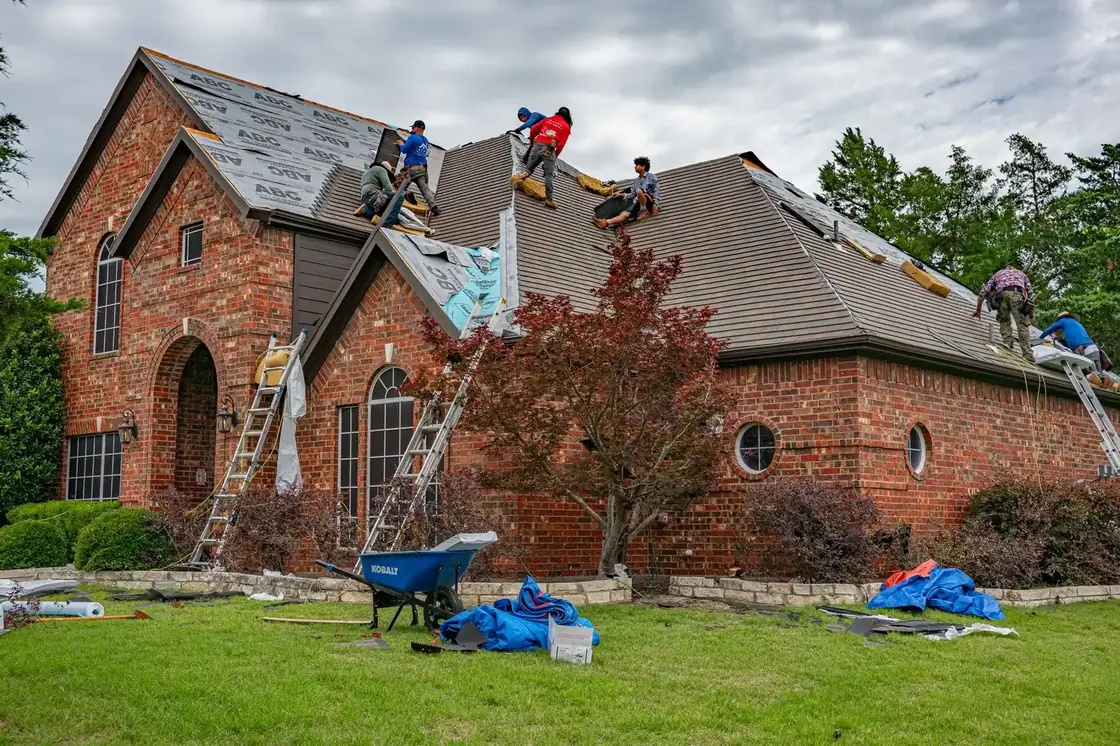 Équipe de couvreurs refaisant la toiture d'une maison en briques
